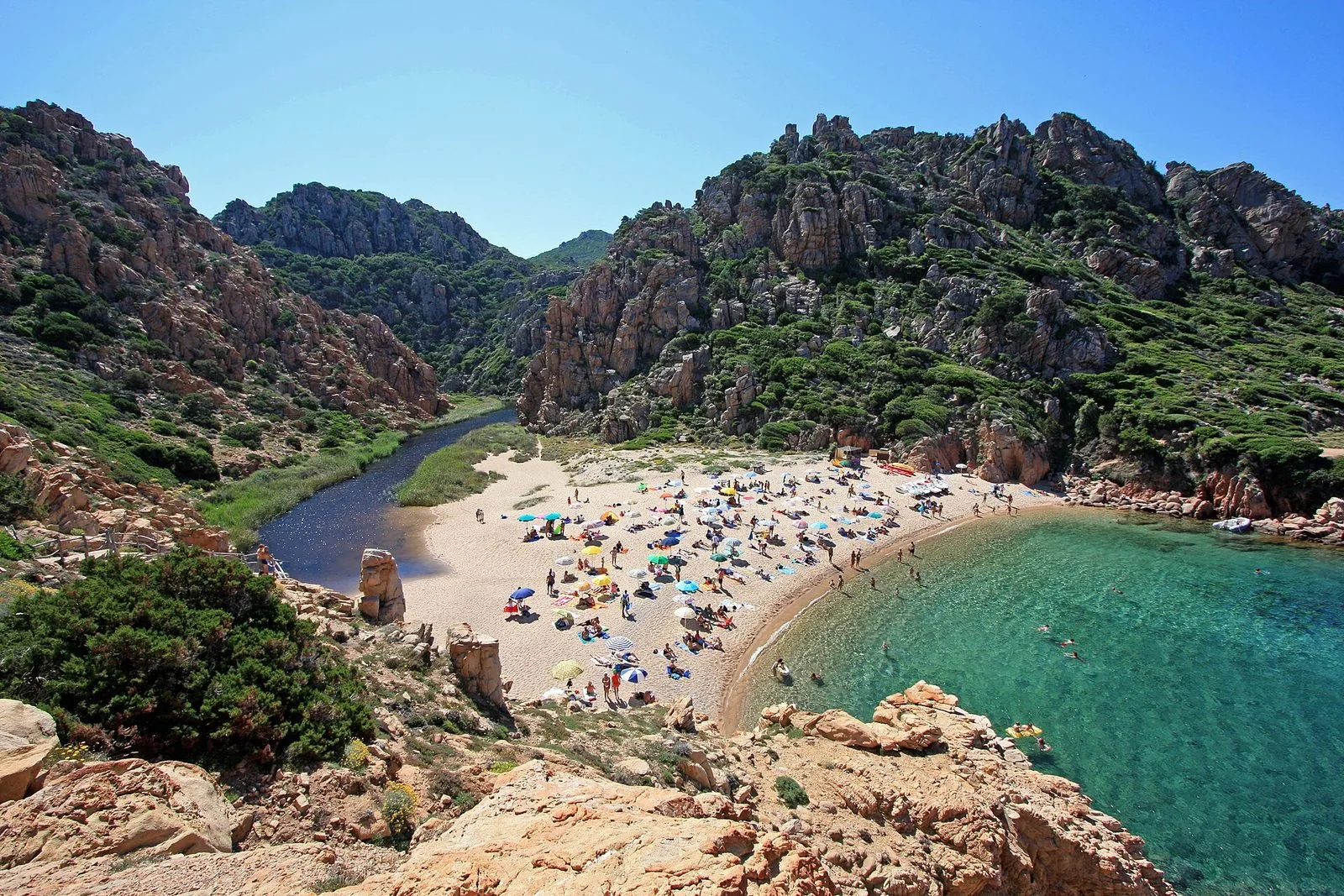 La spiaggia di Li Cossi a Costa Paradiso vista dall'alto, fra rocce rosa, macchia mediterranea e il piccolo fiume che arriva al mare
